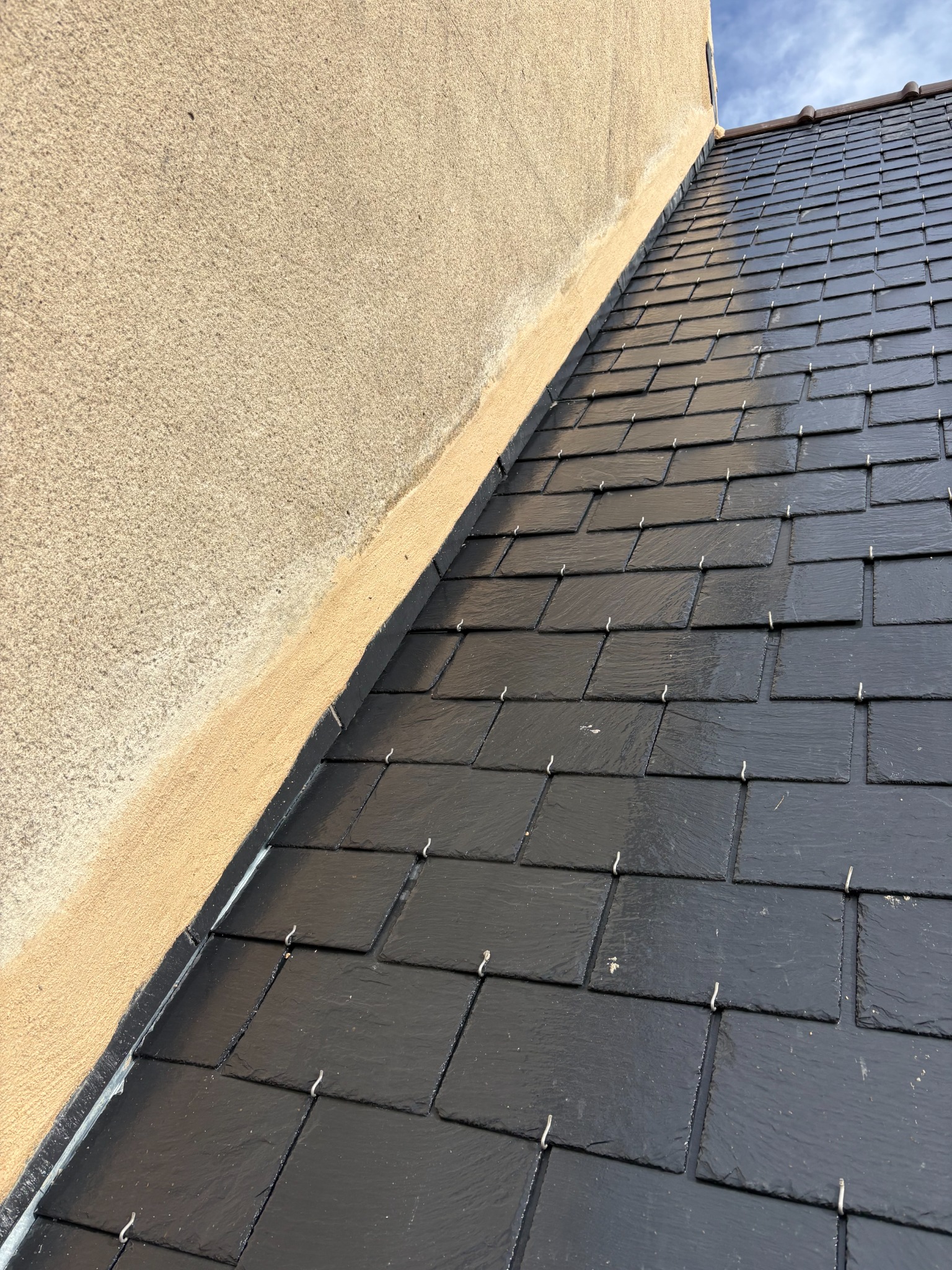 Détail du raccord entre un mur enduit et une couverture en ardoises